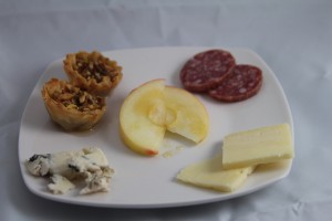 Clockwise from upper left: Mini Baklava, Chianti Salami, Cabot Sharp Cheddar, and Roquefort, with Honey Crisp Apple and Fire Blossom Honey in the middle.